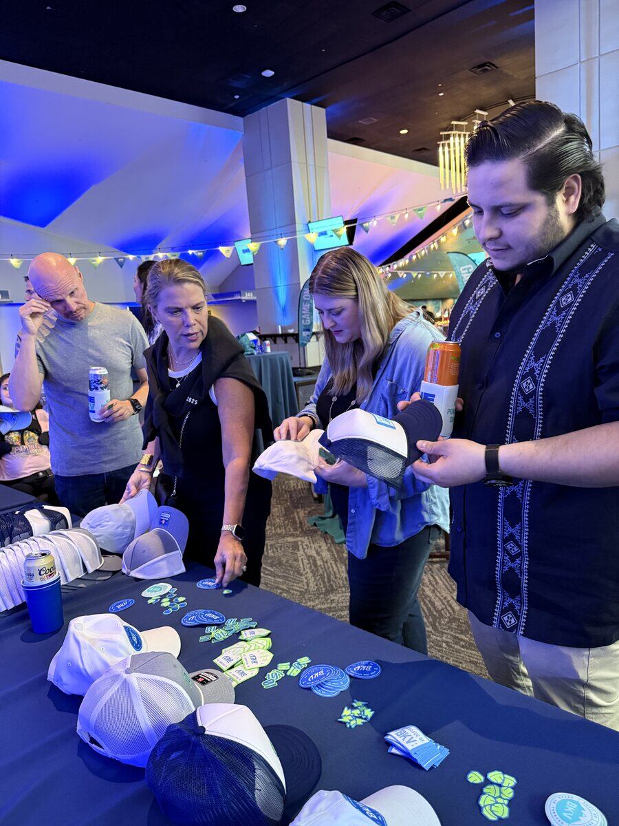 Guests at a stadium club selecting trucker caps and patch letters from a navy table display